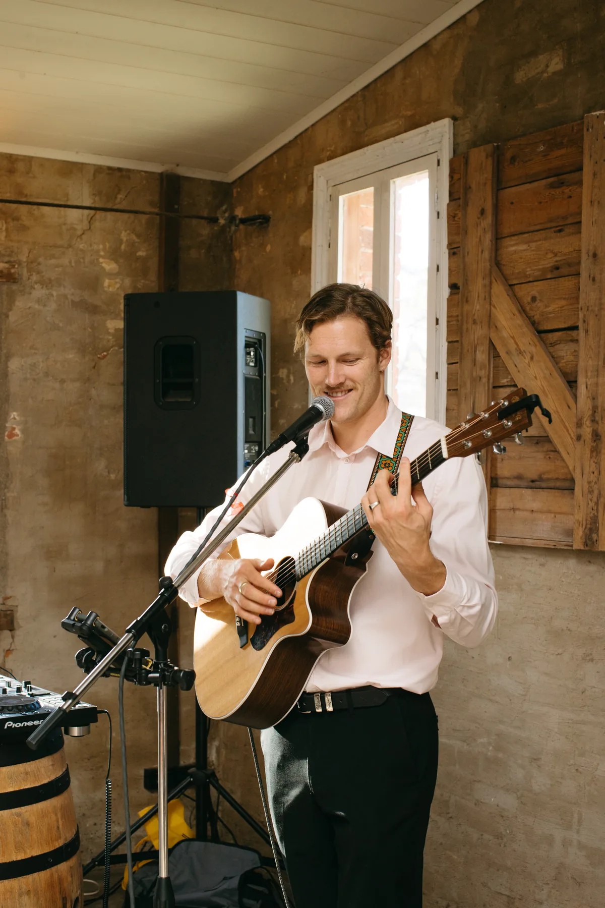 Jem Pryse playing acoustic guitar in a barn