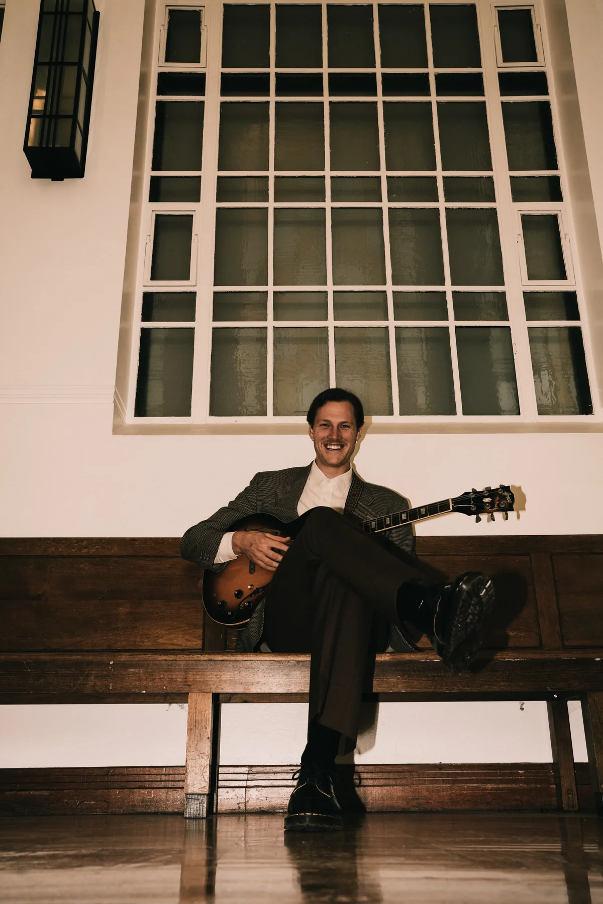 Jem Pryse sitting on a bench with a guitar