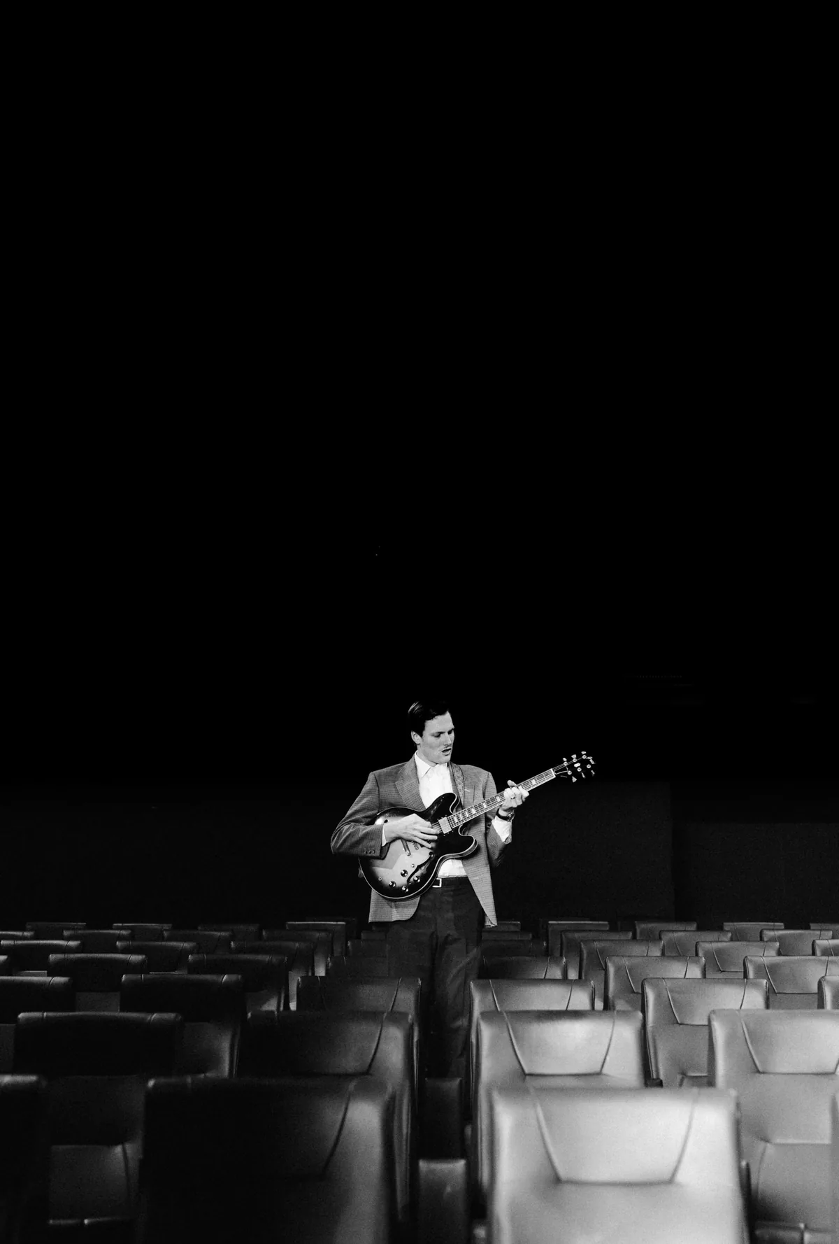 Jem Pryse playing guitar alone in an empty cinema