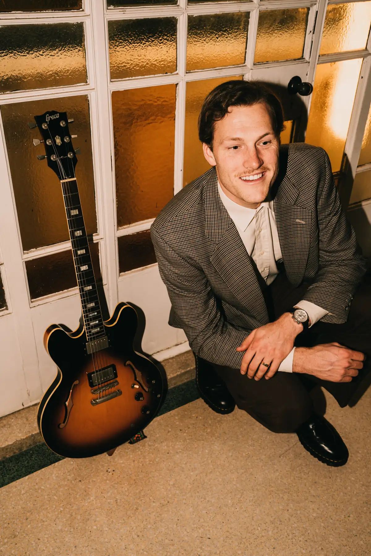 Jem Pryse crouching with his guitar