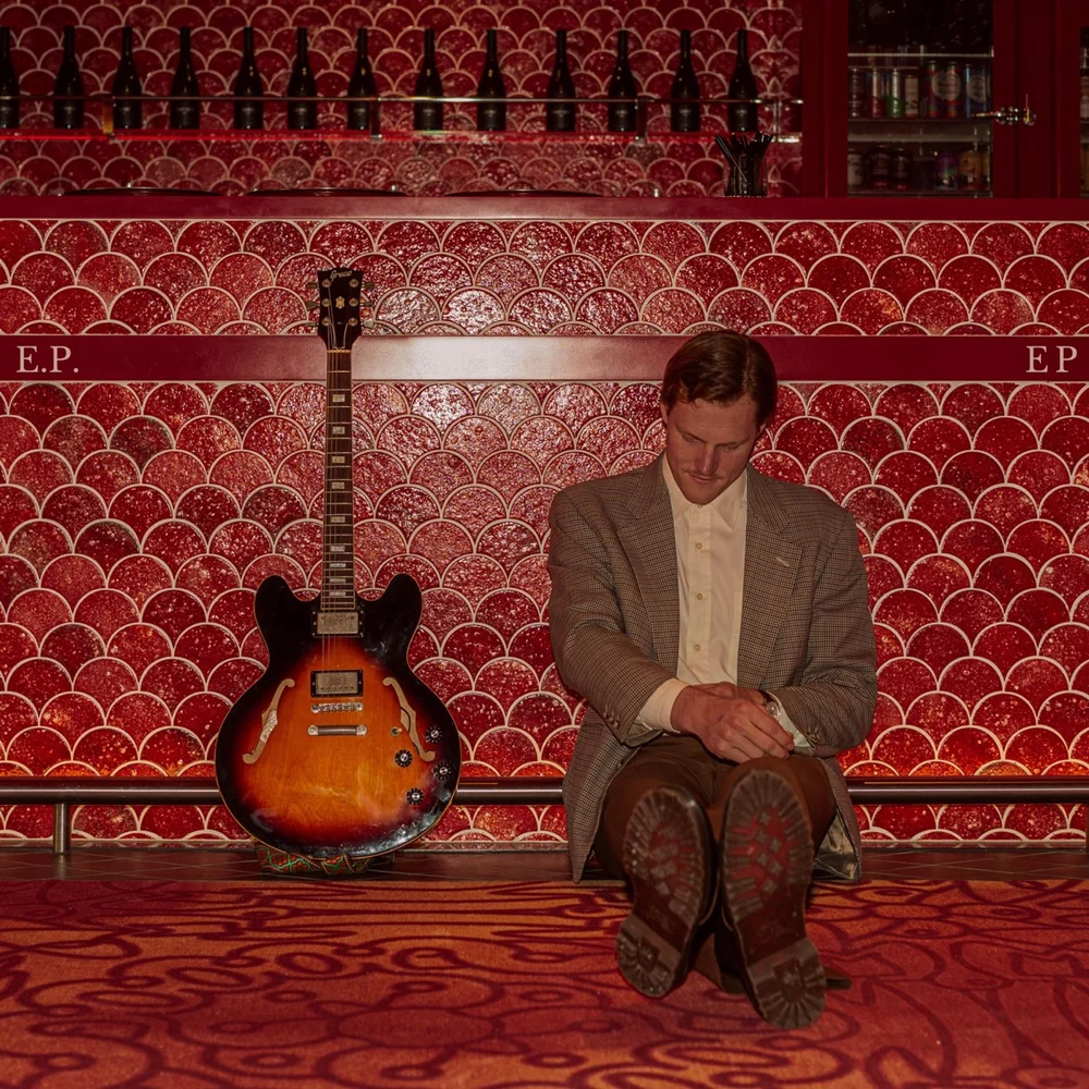 Cover art for Jem Pryse's E.P. — Jem seated at a red-tiled bar with a guitar