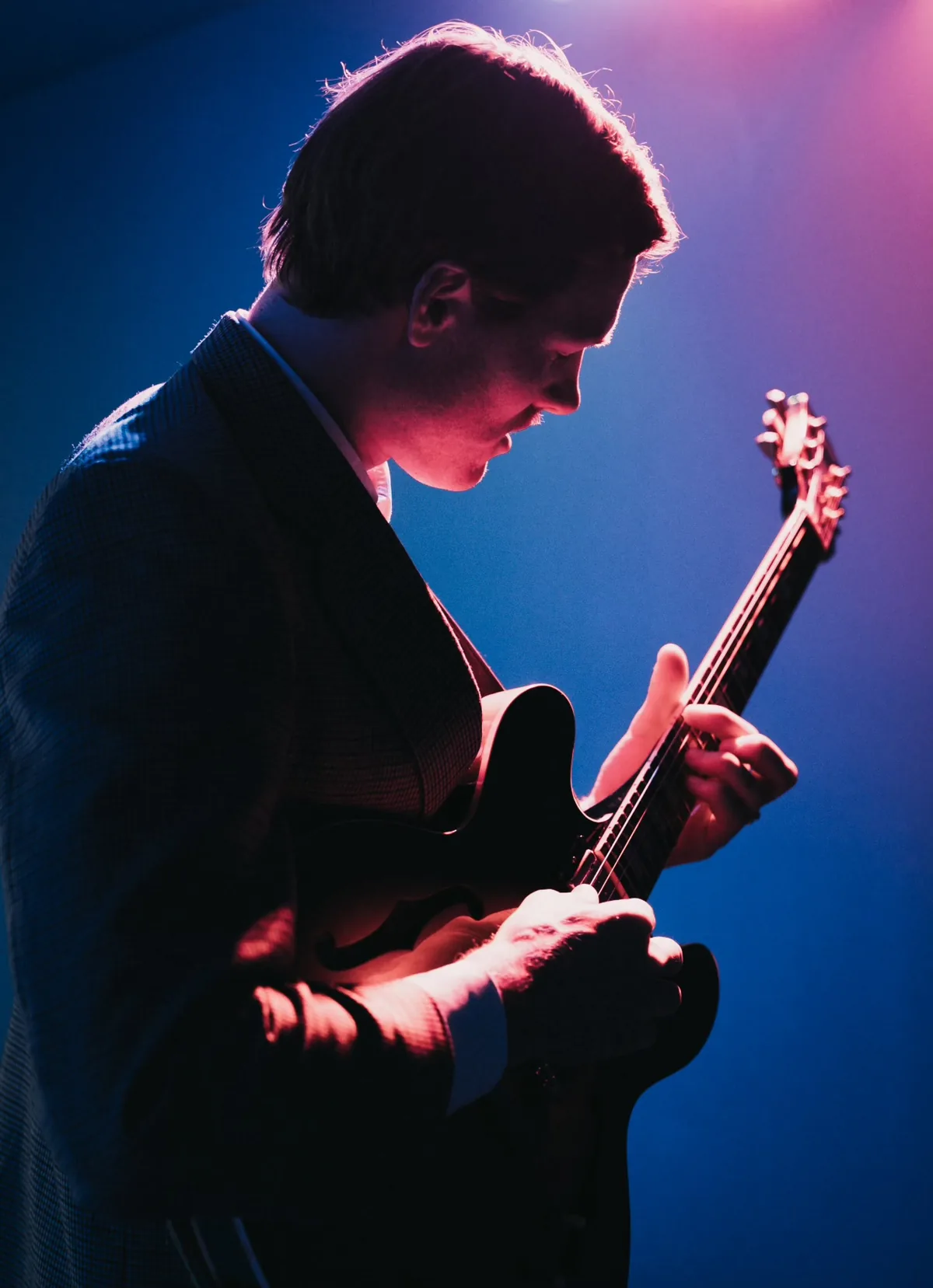 Jem Pryse playing live under coloured stage lights